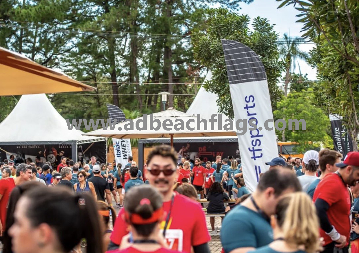 Custom feather advertising flags flying outdoors at a sporting event printed on knitted polyester